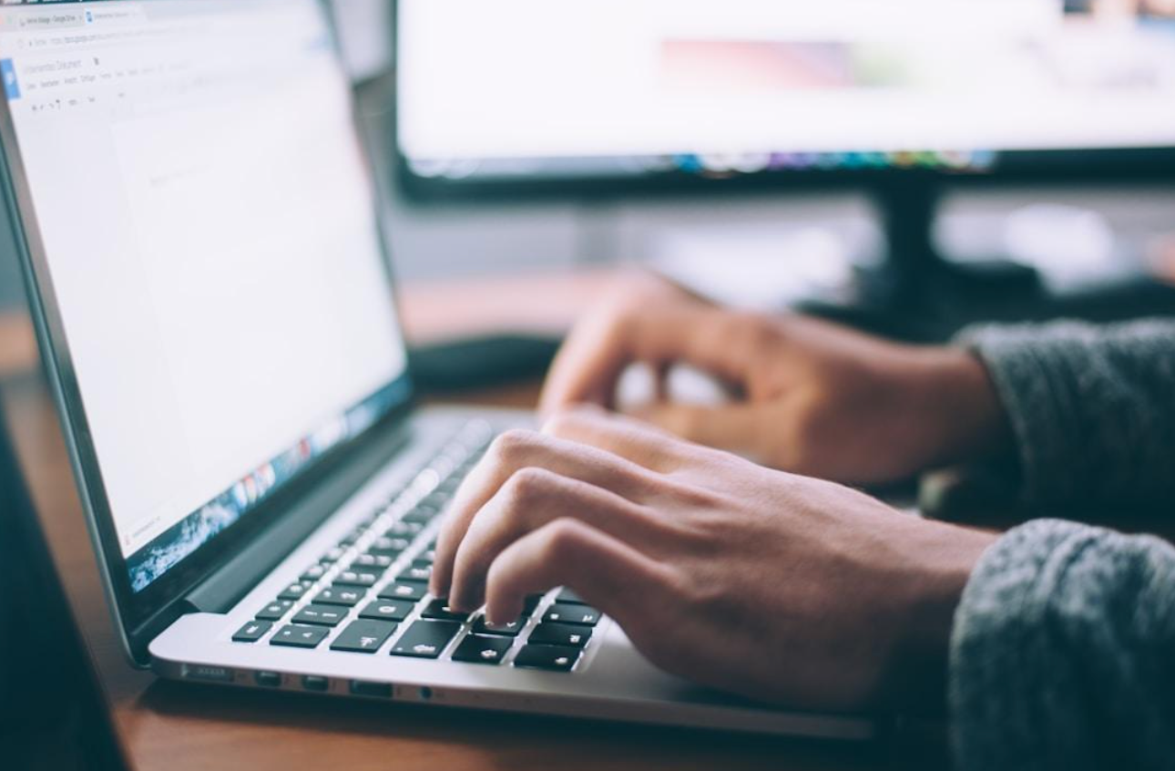 A person typing on a laptop, illustrating the impact of fax technology and online fax services on communication.